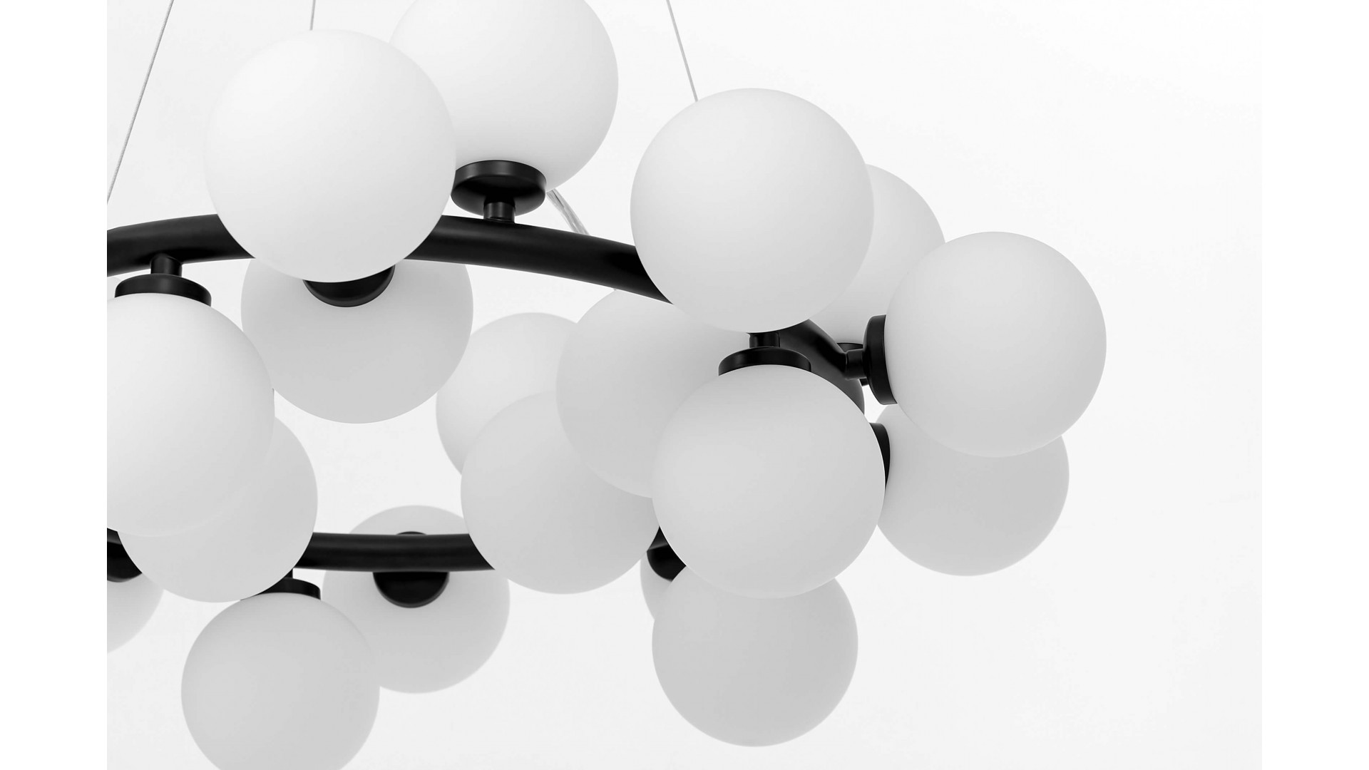 Fragment lampy wiszącej w stylu nowoczesnym z czarną ramą i białymi kulami