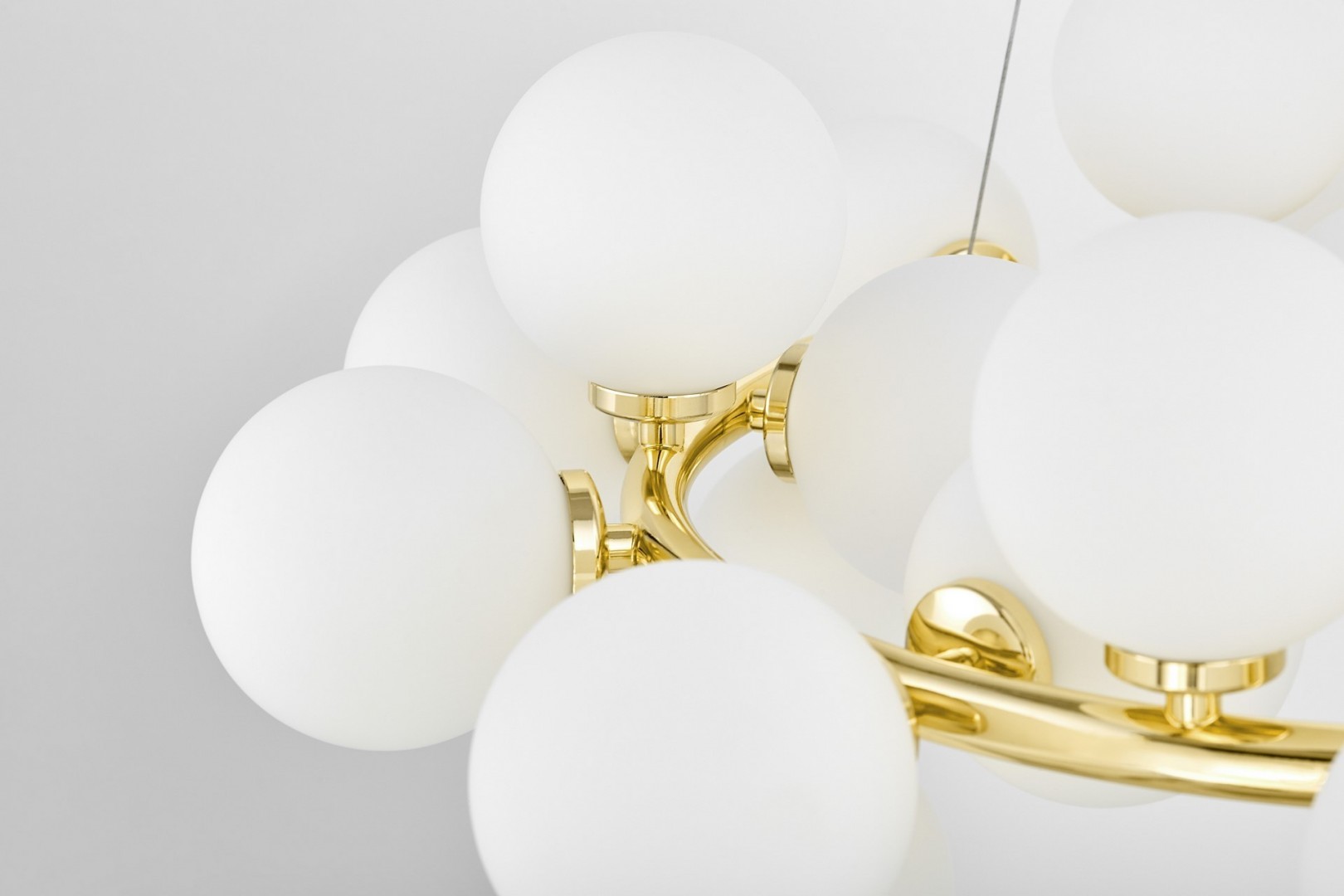 Detal lampy złote ramię i mleczne kule eleganckie oświetlenie