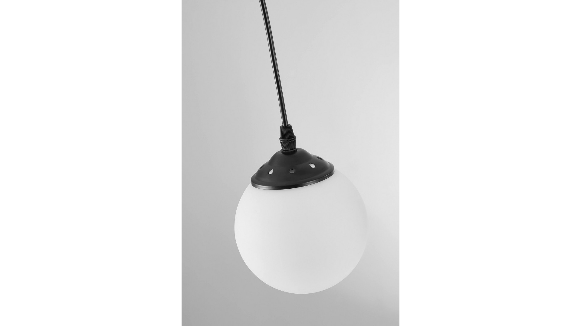 elegancka lampa wisząca z białym kulistym kloszem i czarną opraw dodająca nowoczesnego charakteru wnętrzu