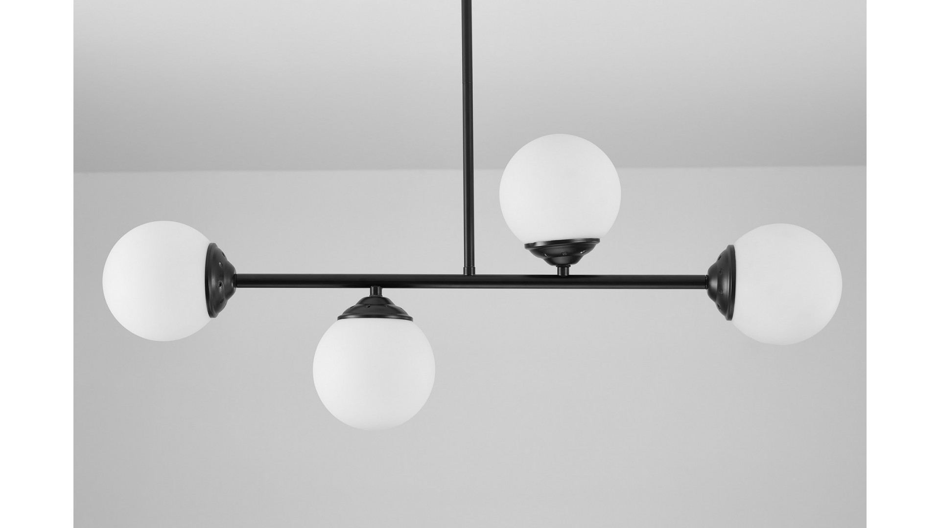 Lampa z czterema kulistymi kloszami w białym szkle, zawieszona na czarnym stelażu. Nowoczesna i elegancka dekoracja wnętrza.