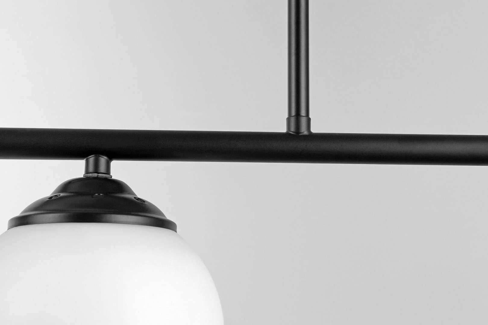 Czarna metalowa konstrukcja lampy wiszącej z kilkoma ramionami i matowymi kloszami w minimalistycznym stylu.