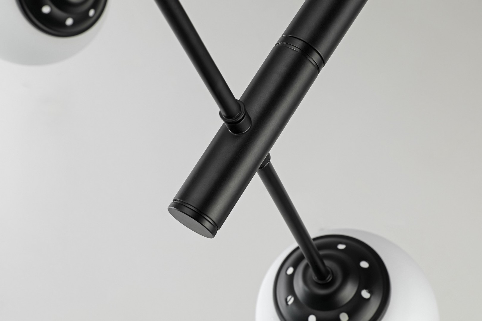 Geometryczne ramiona czarnej lampy wiszącej z kulistymi kloszami w nowoczesnym designie