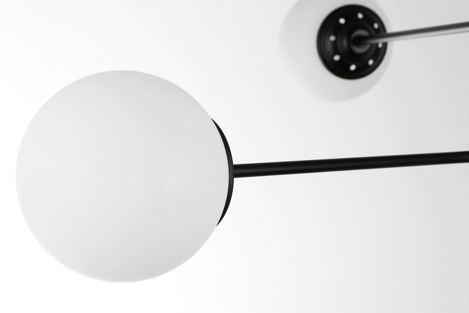 Nowoczesna lampa wisząca z sześcioma mlecznymi kloszami na czarnych ramionach, w stylu geometrycznym.