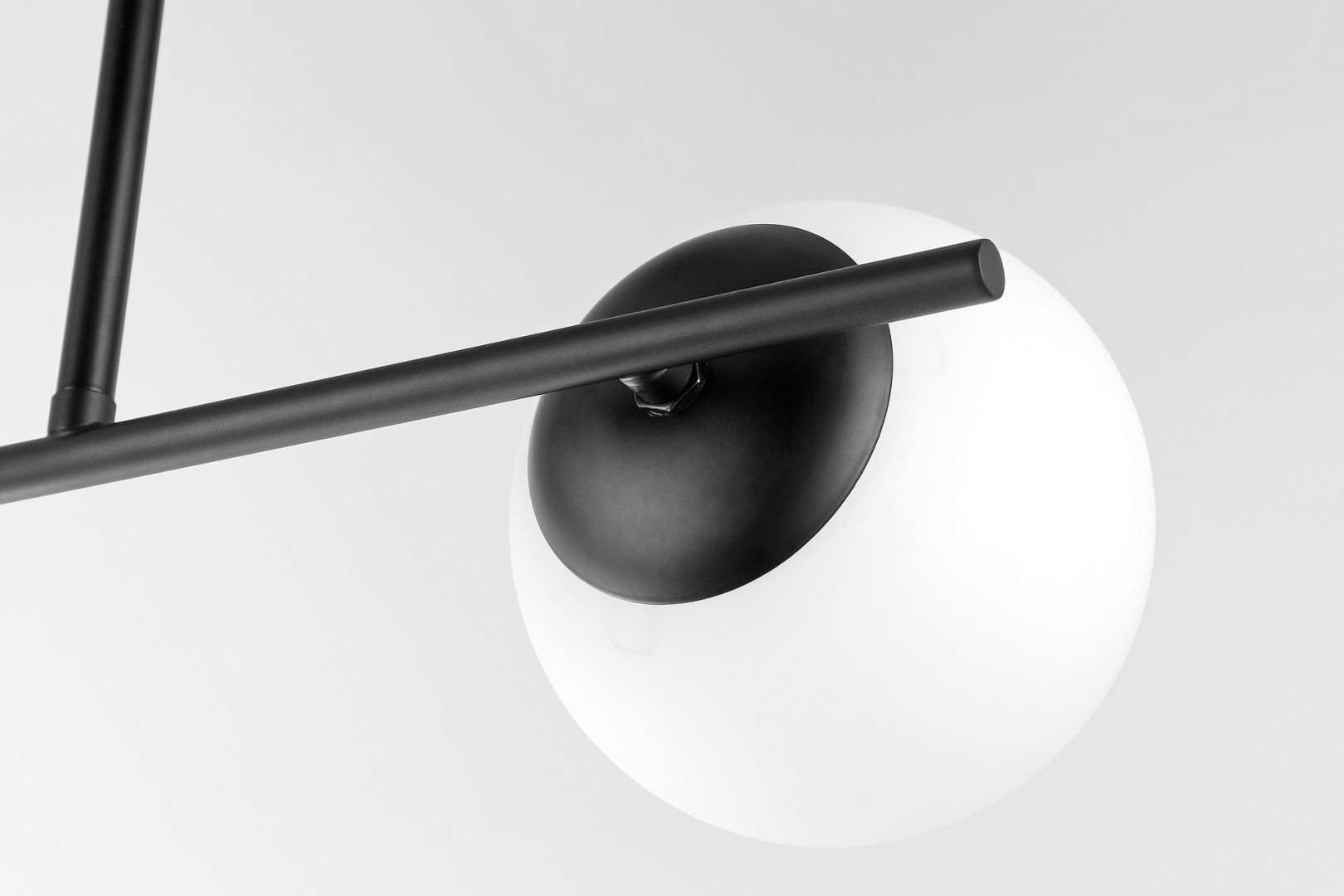 Detal nowoczesnej czarnej lampy sufitowej z matowym kloszem w stylu minimalistycznym i modern loft, ukazujący połączenie ramieni