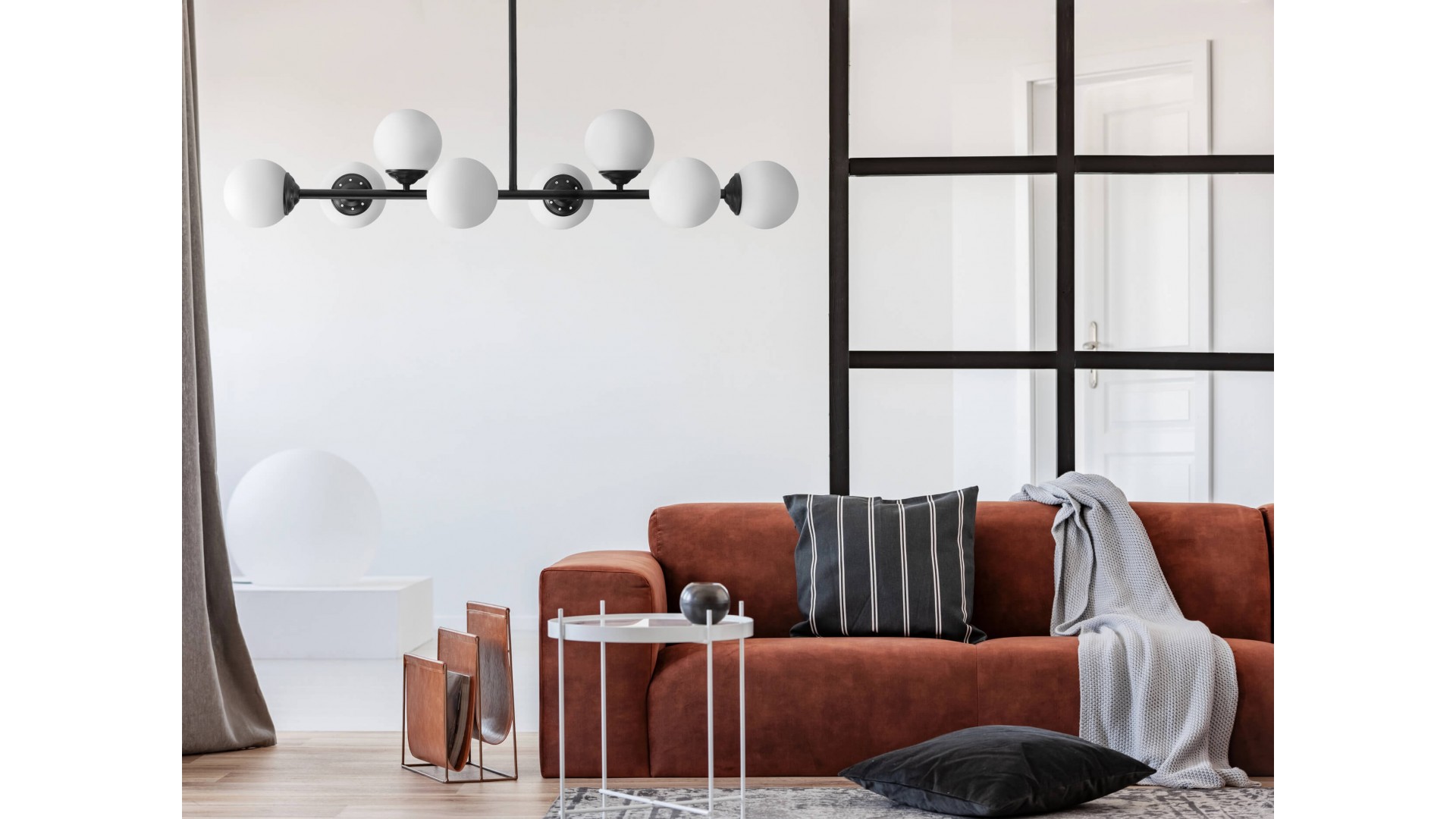 czarna lampa wisząca z ośmioma kulami na ścianie nad rudą sofą w salonie Lampit model FINO 8 LED