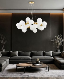 Nowoczesna mosiężna lampa wisząca Marsiada 25 z białymi kulami, zawieszona nad ciemnoszarym narożnikiem w eleganckim salonie