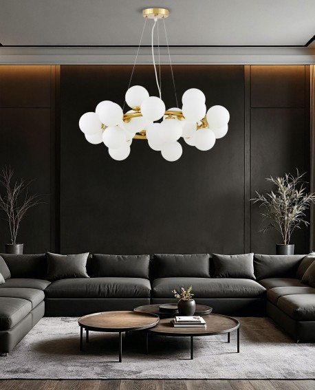 Nowoczesna mosiężna lampa wisząca Marsiada 25 z białymi kulami, zawieszona nad ciemnoszarym narożnikiem w eleganckim salonie