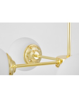  Złota oprawa lampy z matowym, kulistym kloszem osadzonym na błyszczącej, perforowanej podstawie ramienia.