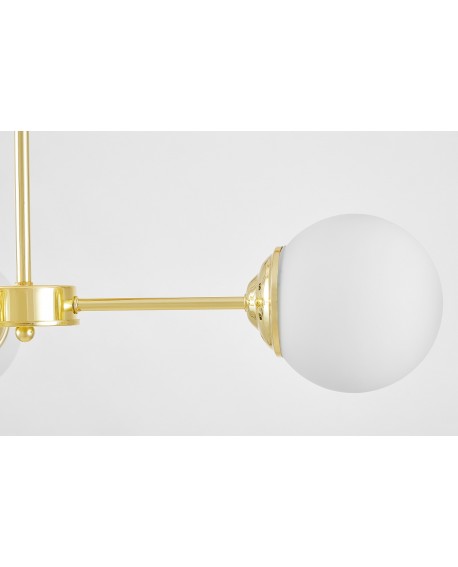 Zbliżenie na złote wykończenie mocowania lampy z białym kloszem, podkreślające elegancki detal