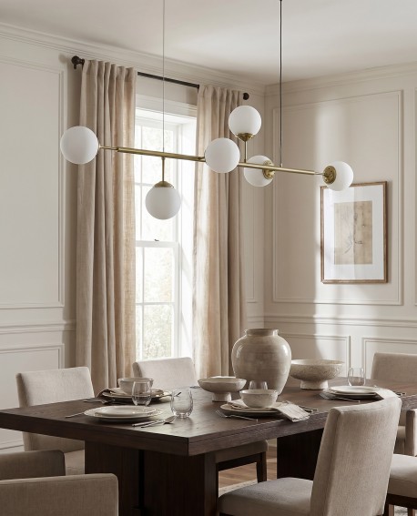  Designerska lampa FINO w złocie o linearnej formie zawieszona nad stołem w luksusowej kuchni modern