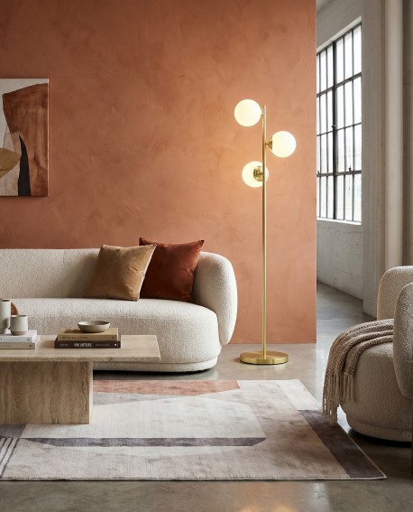 Lampa podłogowa FINO W3 marki Lampit w złotej odsłonie idealnie wpisuje się w nowoczesny salon z beżową sofą