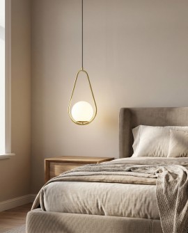 Oświetlenie w formie złotej lampy wiszącej z kulistym kloszem koło łóżka