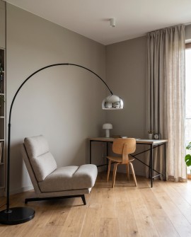 Stojąca lampa łukowa oświetla gabinet z biurkiem i fotelem
