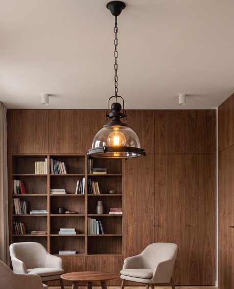 Czarna lampa sufitowa nad stolikiem w domowej bibliotece z regałami
