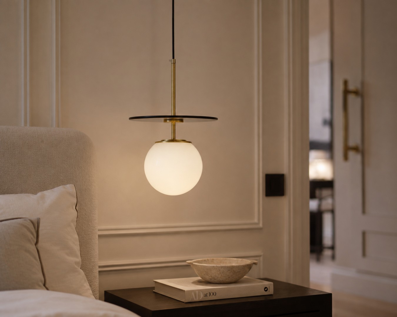 Biała kula ze złotym szczotkowanym wykończeniem jako wisząca lampa nocna Daltona w nowoczesnej sypialni